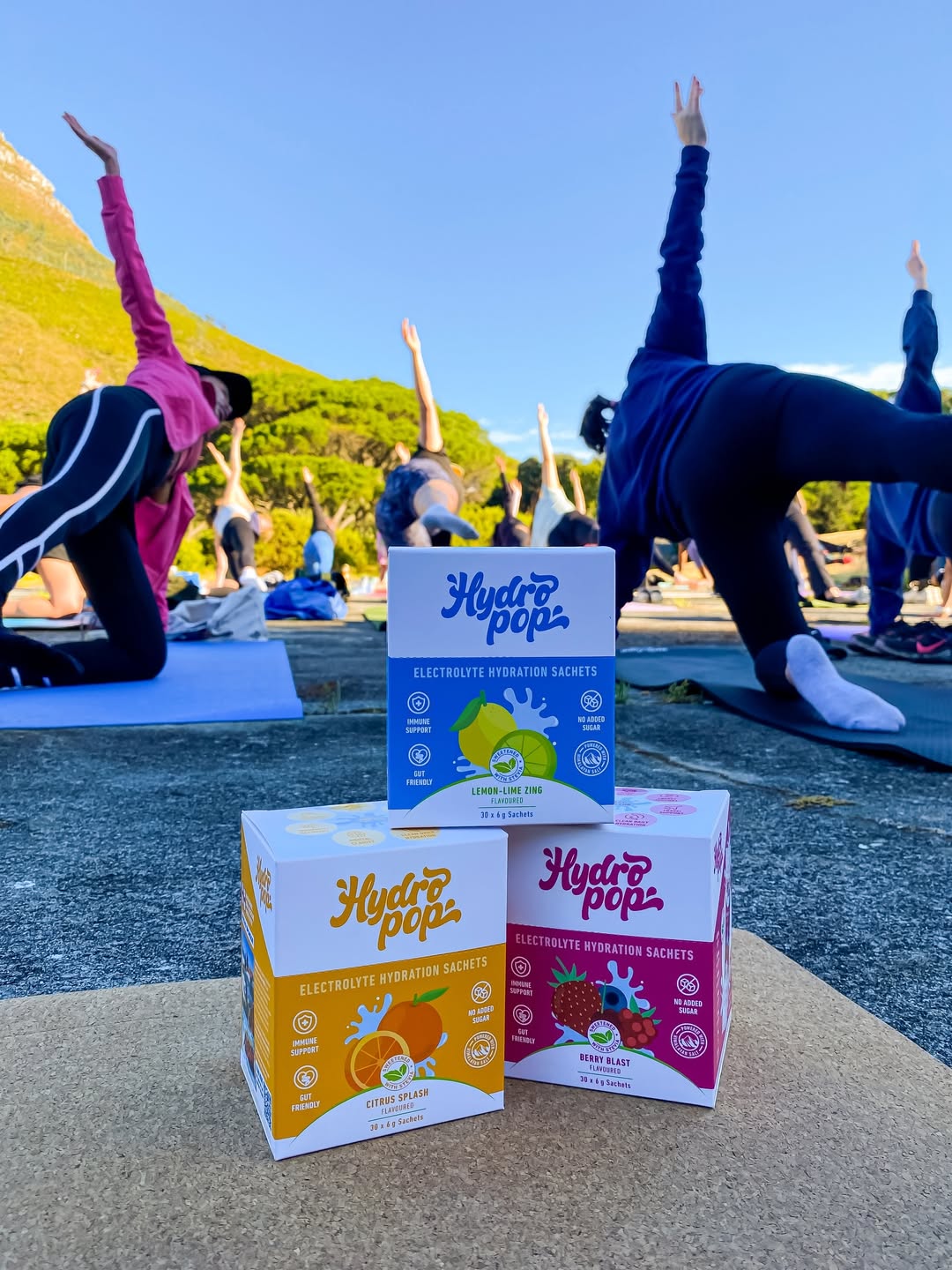 Hydropop Daily electrolytes with women doing yoga in the background in nature