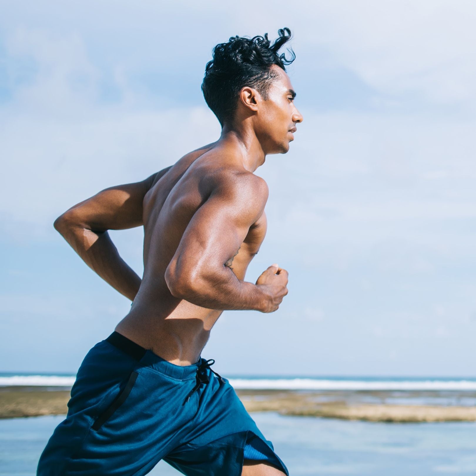 Man running on a beach with a clear sky