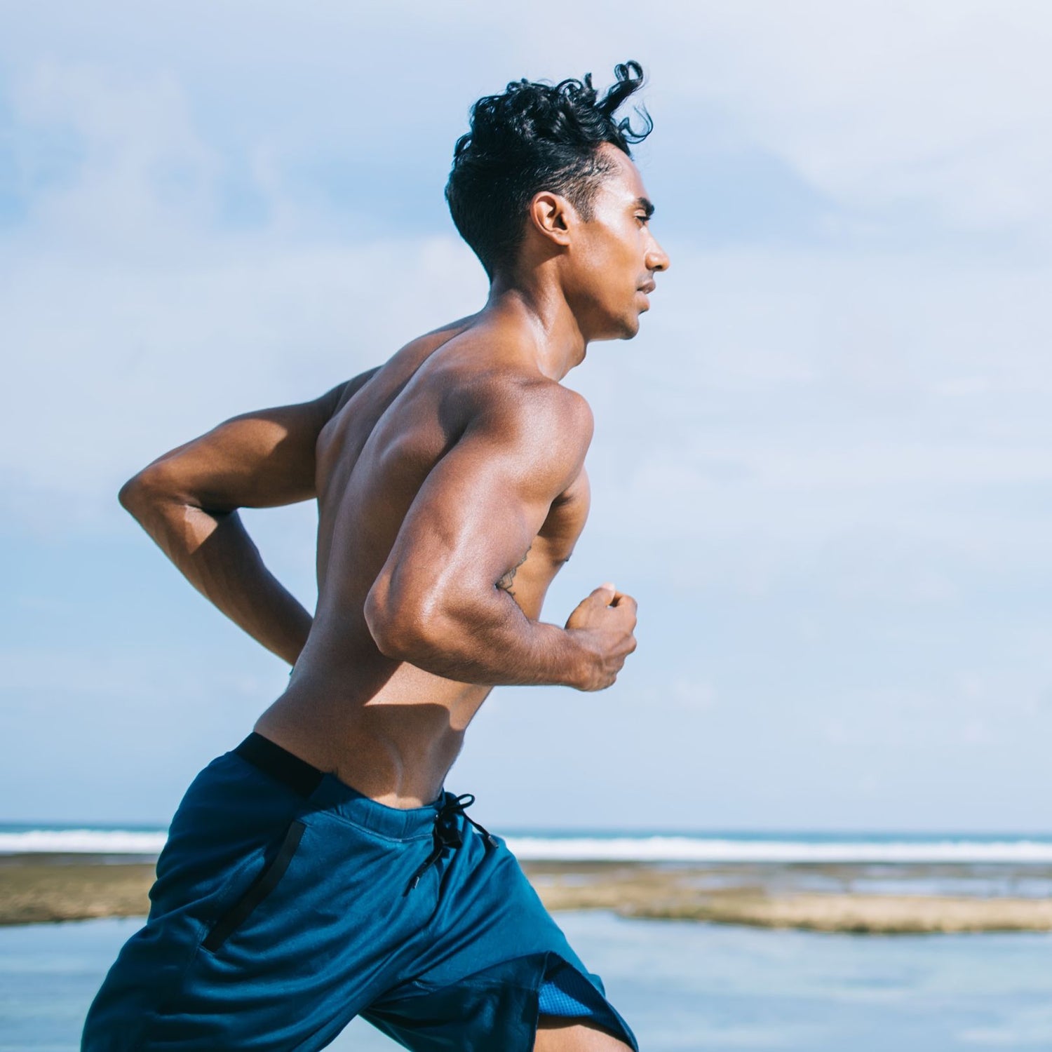Man running on a beach with a clear sky