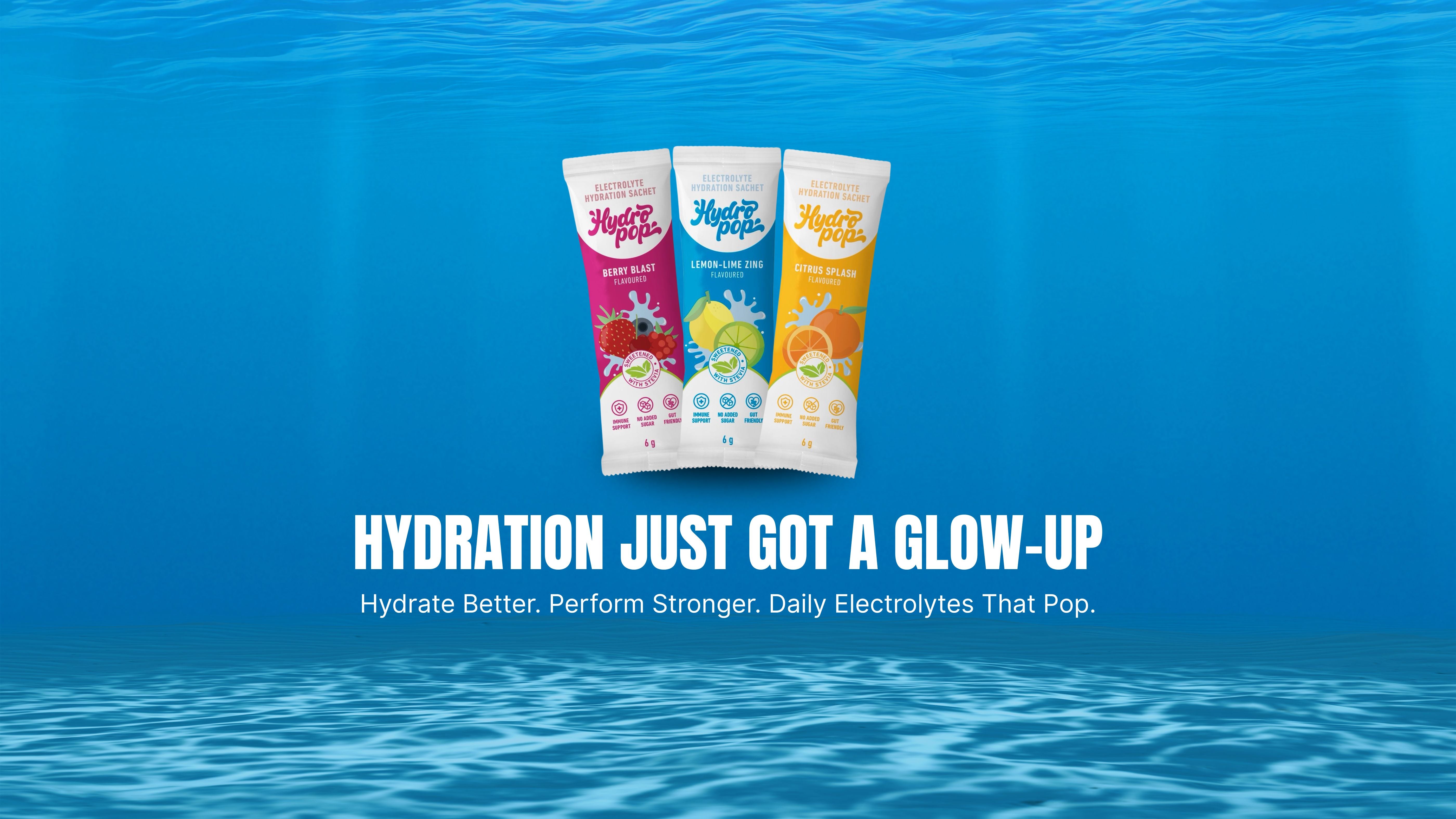 Three colorful packets of Hydropop Daily electrolytes on a blue underwater background with text: Hydrate Better. perform Stronger. Daily Electrolytes That Work.